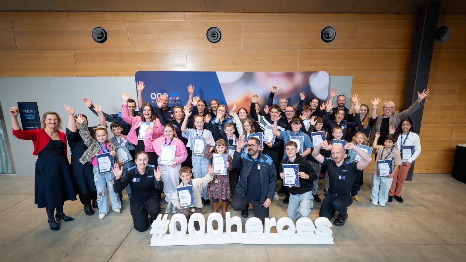 Group shot of Call-Takers and their heroes holding up their arms