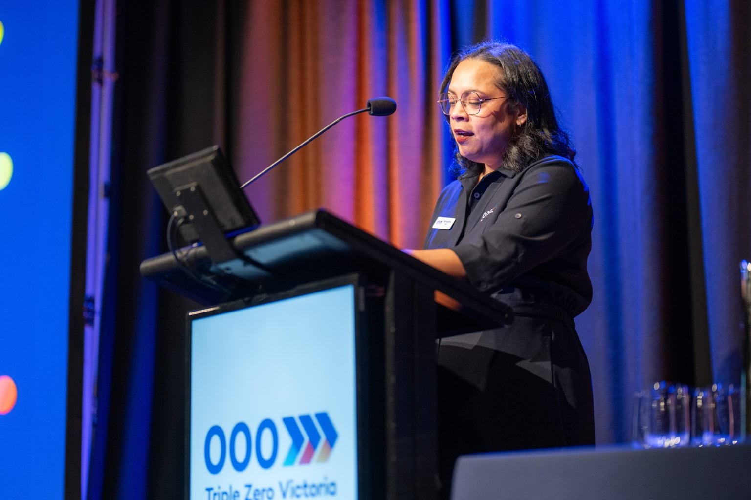A women standing in behind a lectern MC the event