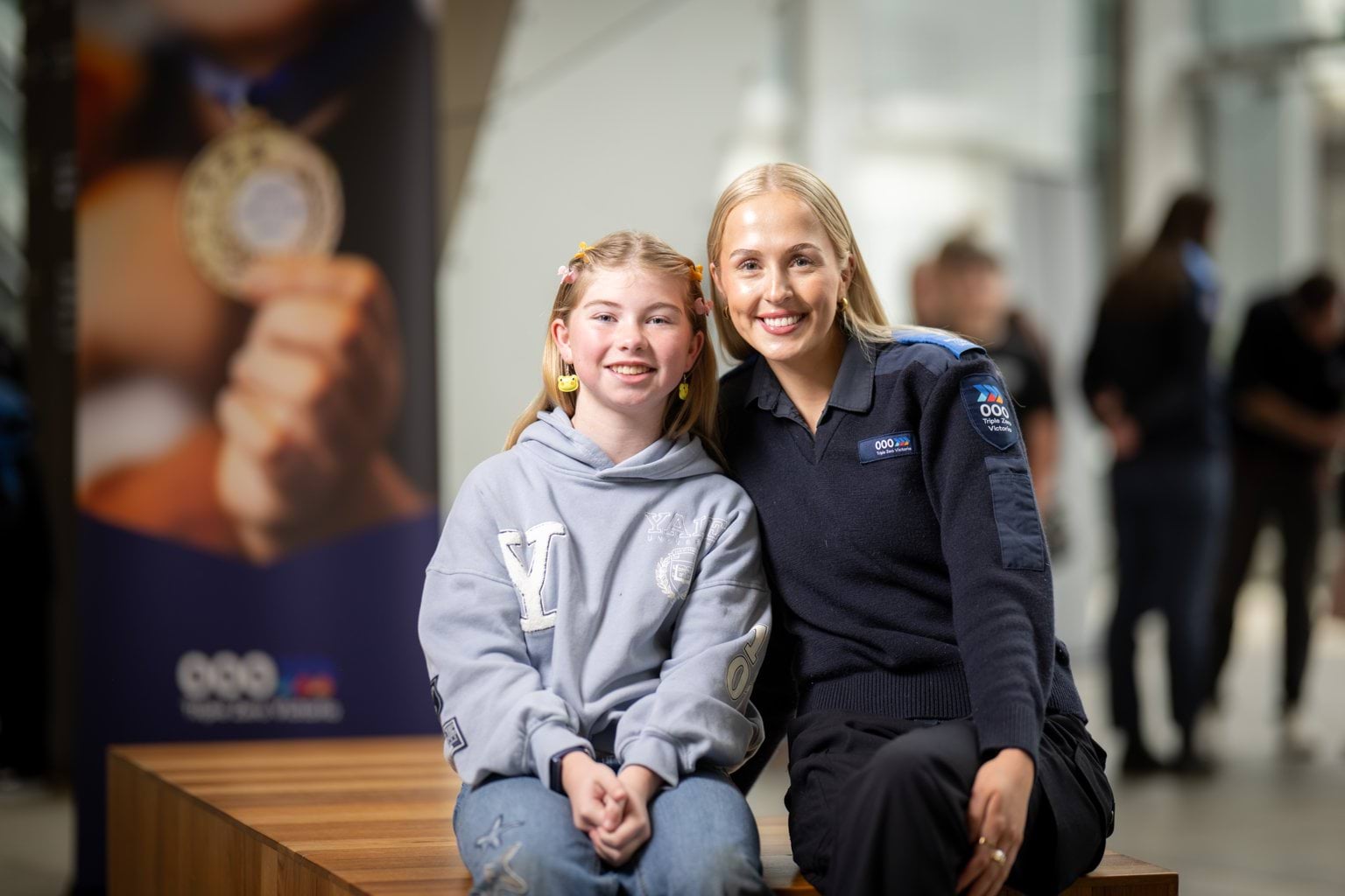 A young girl sits with a female Call-Taker smiling at camera