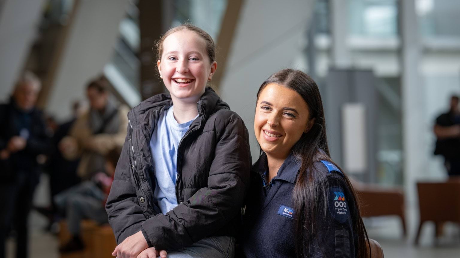A young girl sits with a female Call-Taker smiling at camera