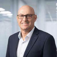 Profile picture of Triple Zero Victoria's Chief Executive Officer David Clayton. A middle aged man with a bald head wearing a suit and glasses. 