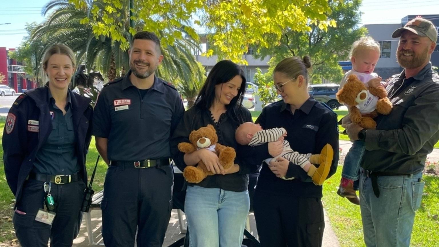 A group shot with Mica paramedics Steph & Jeremy, mum Tayla, call-taker Monet, baby Jimmy and big sister Dottie and Dad Jack